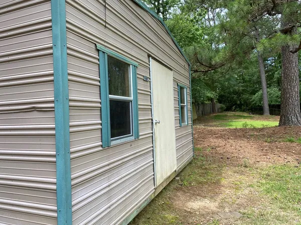 a view of a small house with backyard and a large tree