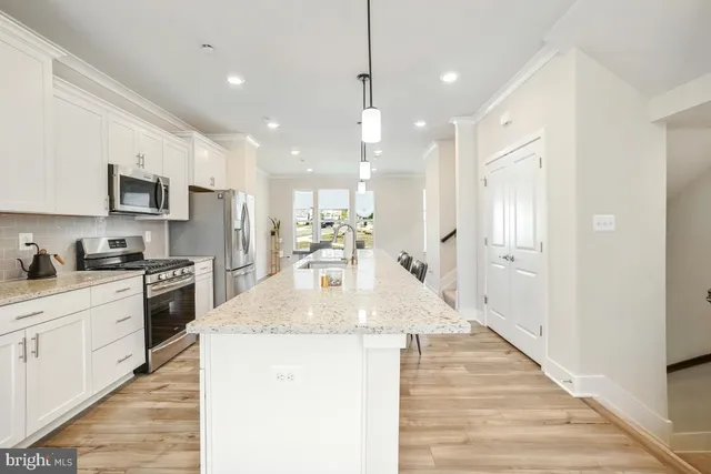 a large kitchen with stainless steel appliances kitchen island a stove a sink dishwasher a refrigerator white cabinets and wooden floor