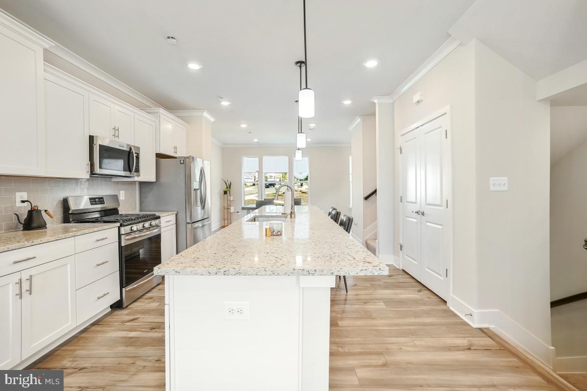 3027 Coriander Place Bryans Road, MD 20616 - Photo 11 of 29 a large kitchen with stainless steel appliances kitchen island a stove a sink dishwasher a refrigerator white cabinets and wooden floor