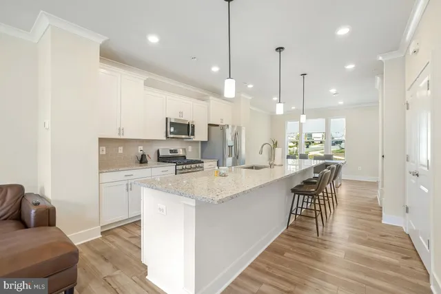 a kitchen with stainless steel appliances kitchen island granite countertop a sink a stove and a refrigerator