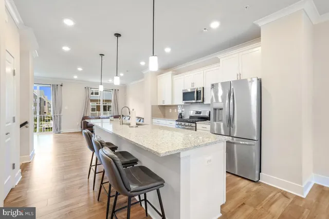 a kitchen with stainless steel appliances a refrigerator a sink dishwasher a stove and a dining table with wooden floor