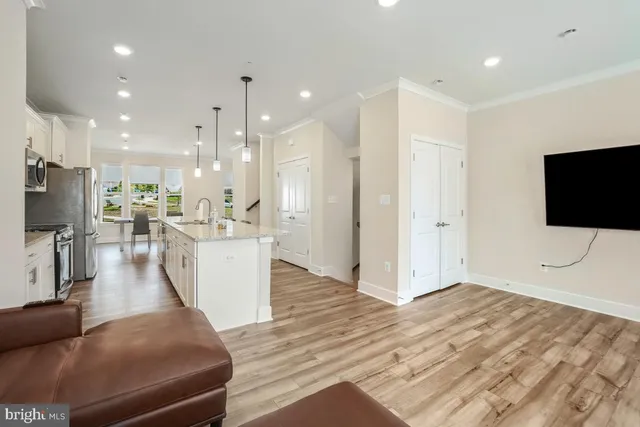 a living room with stainless steel appliances furniture and a flat screen tv