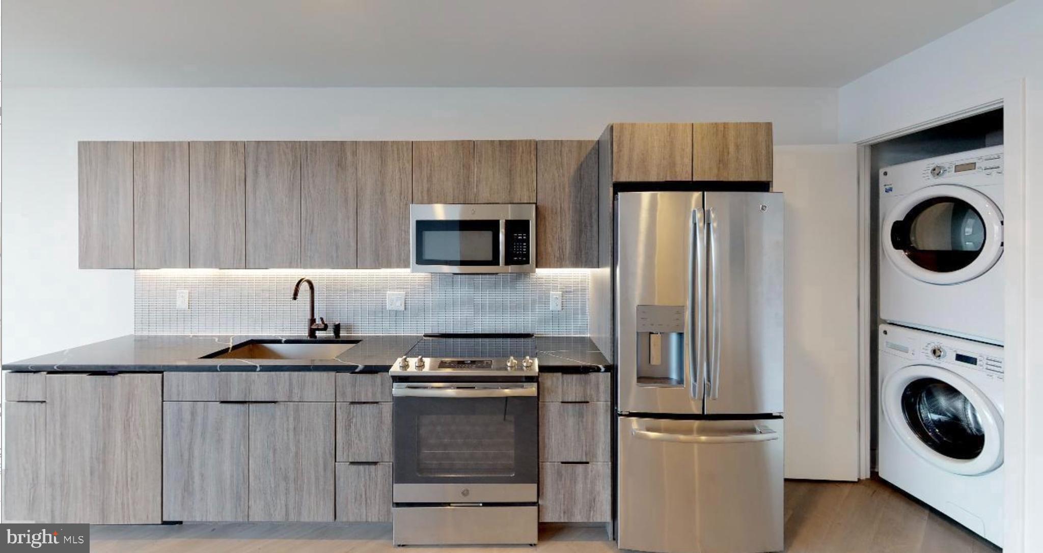 1 Brown Street, Unit STUDIO Philadelphia, PA 19123 - Photo 1 of 14 a kitchen with kitchen island a stove a refrigerator and a sink with wooden cabinets