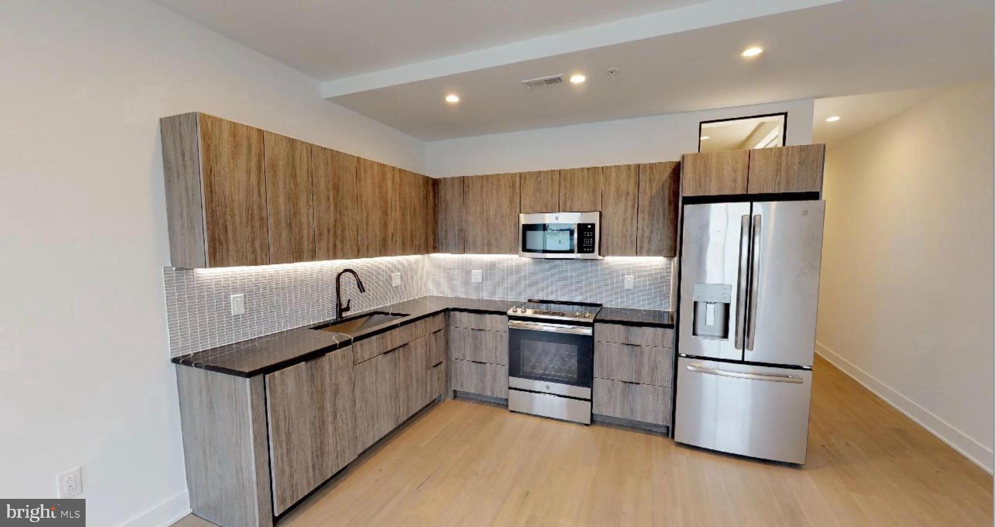 1 Brown Street, Unit STUDIO Philadelphia, PA 19123 - Photo 8 of 14 a kitchen with stainless steel appliances granite countertop a refrigerator a stove and a microwave