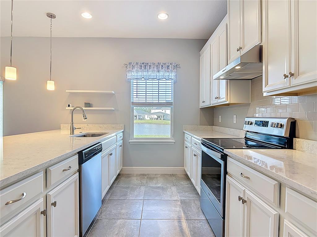 5644 Estero Loop Port Orange, FL 32128 - Photo 4 of 50 a kitchen with stainless steel appliances granite countertop a sink and dishwasher a stove top oven with white cabinets