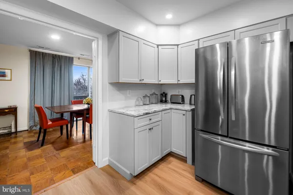 a kitchen with stainless steel appliances granite countertop a refrigerator a stove and white cabinets with wooden floors