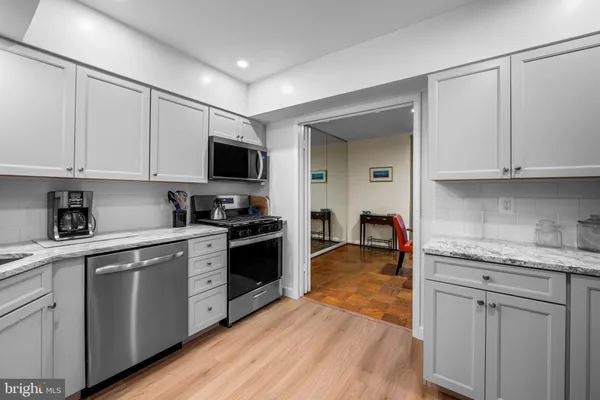 a kitchen with granite countertop white cabinets and stainless steel appliances