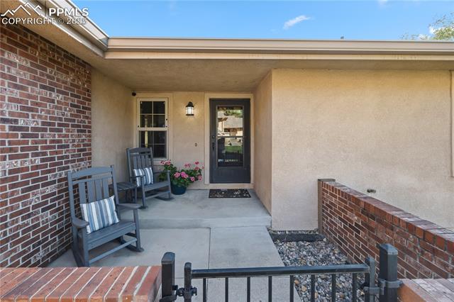 2135 Glenhill Road Colorado Springs, CO 80906 - Photo 4 of 50 Entrance to property featuring stucco siding, brick siding, and a porch