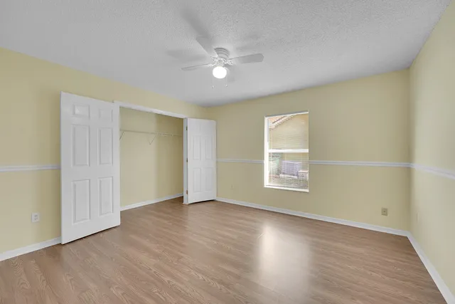 an empty room with wooden floor and windows