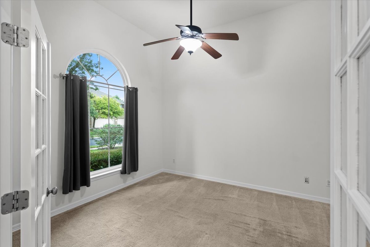 2304 Village View Loop Pflugerville, TX 78660 - Photo 23 of 40 A spacious room offers comfortable carpeting and a distinctive arched window, perfect for a dedicated home office.