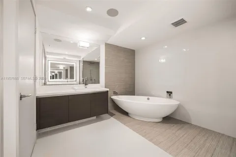 a spacious bathroom with a double vanity sink toilet mirror and bathtub