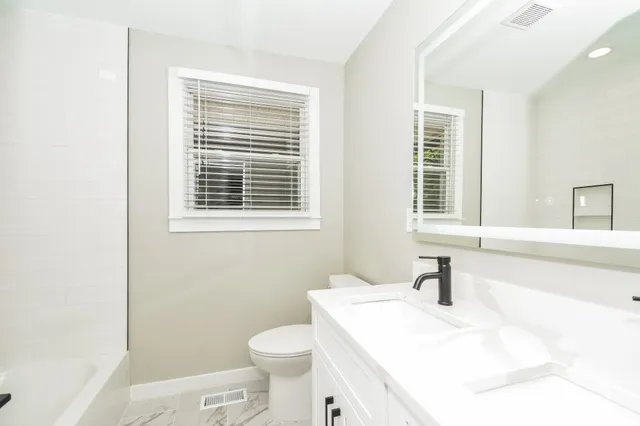 a bathroom with a sink a toilet and a window