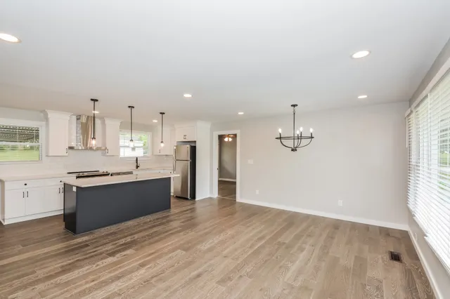 a large kitchen with stainless steel appliances granite countertop a stove and a wooden floors