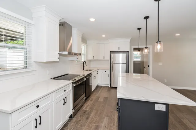 a kitchen with stainless steel appliances kitchen island granite countertop a sink a stove and a refrigerator