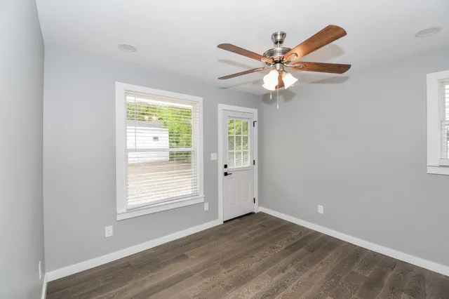 a view of an empty room with window and wooden floor