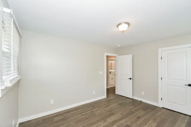 a view of an empty room with wooden floor and windows