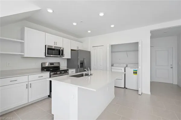 a kitchen that has a refrigerator a sink a stove and white cabinets