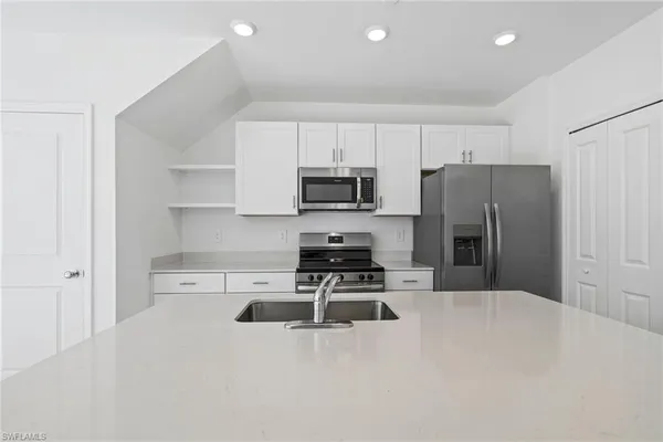 a kitchen with granite countertop a refrigerator and a stove top oven