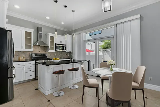 a kitchen with stainless steel appliances granite countertop a stove top oven a sink dishwasher a dining table and chairs with wooden floor