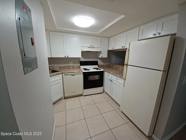a white refrigerator freezer and a stove sitting inside of a kitchen