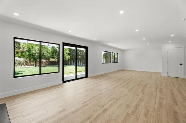 a view of an empty room with a window and wooden floor