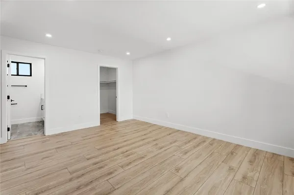a view of an empty room with wooden floor and closet
