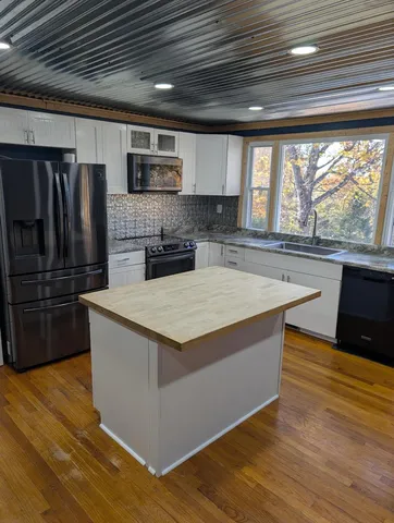 a kitchen with stainless steel appliances granite countertop a sink a stove and a wooden floors