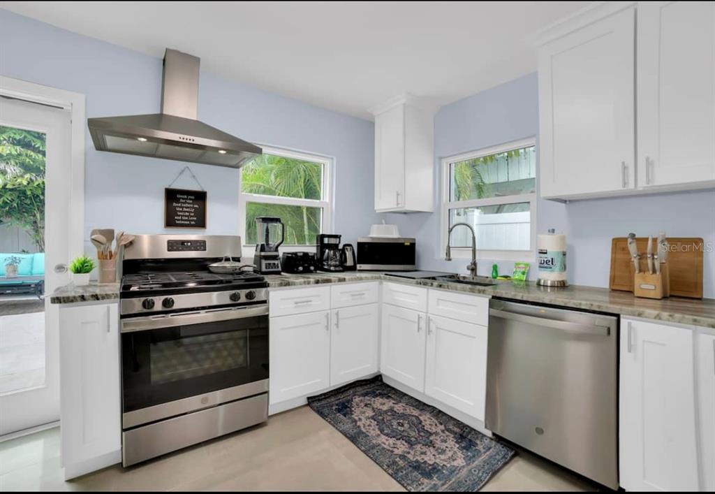 1210 Bay Palm Boulevard Indian Rocks Beach, FL 33785 - Photo 13 of 19 a kitchen with stainless steel appliances granite countertop a stove a sink and a microwave