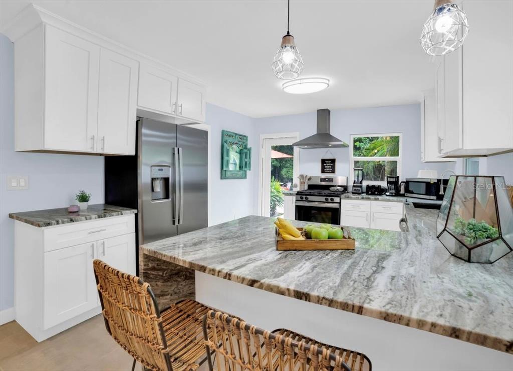 1210 Bay Palm Boulevard Indian Rocks Beach, FL 33785 - Photo 15 of 19 a kitchen with stainless steel appliances granite countertop a stove a refrigerator a sink a dining table and chairs