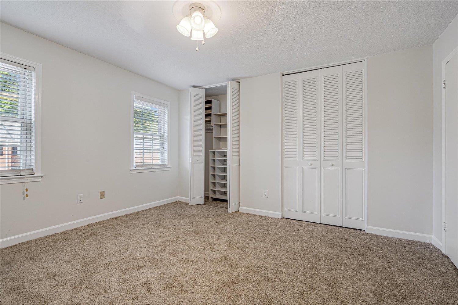 5696 Quince Road, Unit 1 Memphis, TN 38119 - Photo 17 of 26 Unfurnished bedroom featuring two closets, carpet floors, and a textured ceiling