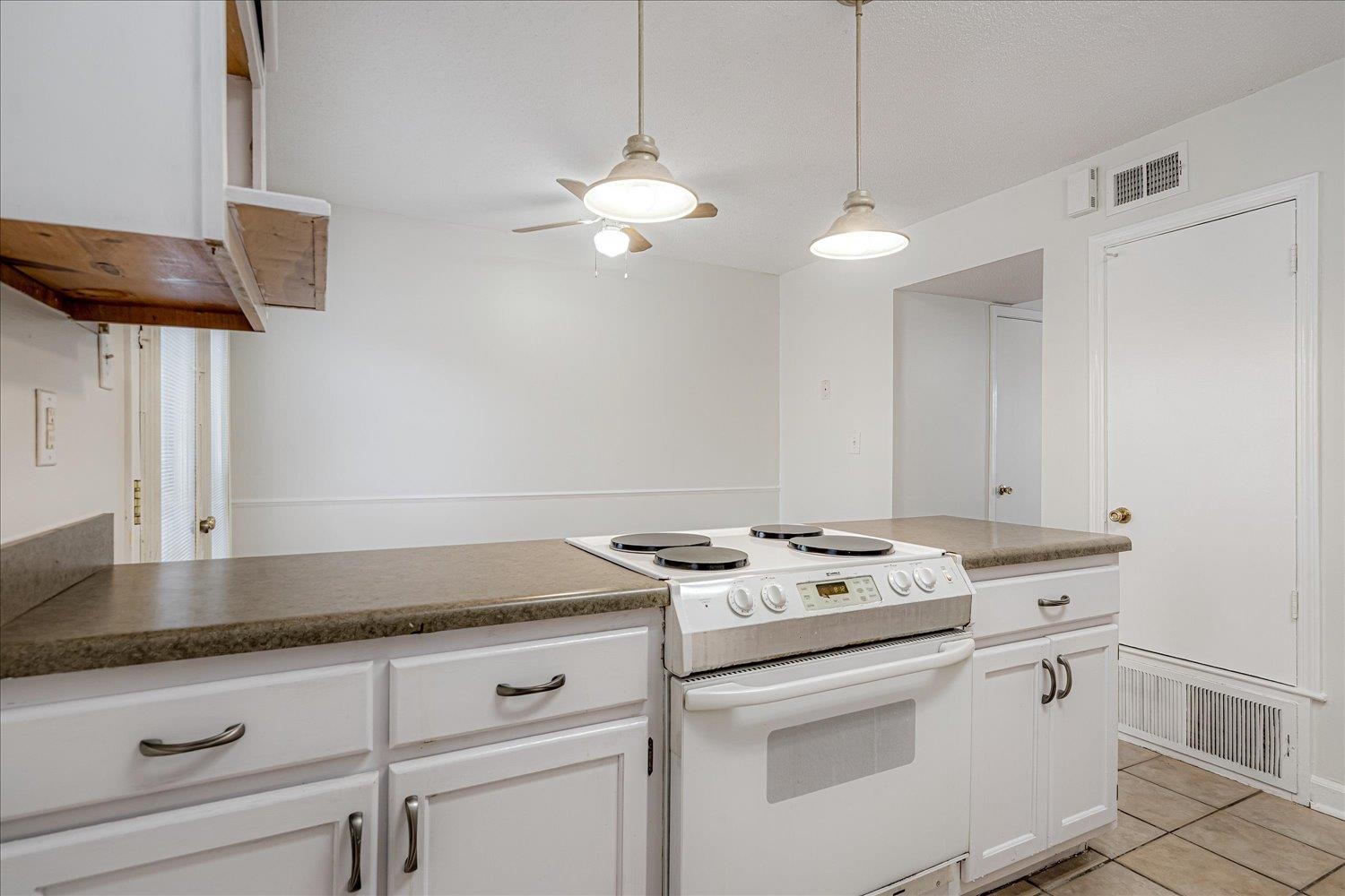 5696 Quince Road, Unit 1 Memphis, TN 38119 - Photo 22 of 26 Kitchen featuring white electric range oven, dark countertops, light tile patterned floors, white cabinetry, and decorative light fixtures