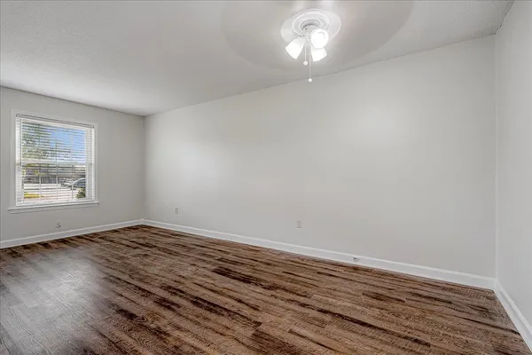 an empty room with wooden floor and windows