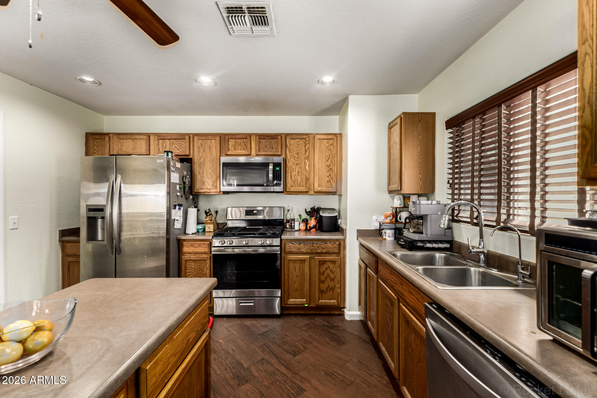 40264 West Lococo Street Maricopa, AZ 85138 - Photo 24 of 29 a kitchen with stainless steel appliances granite countertop a sink stove microwave refrigerator and cabinets