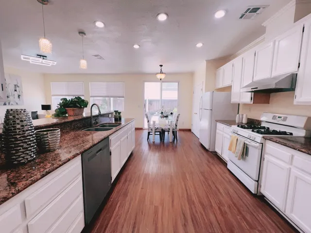 a kitchen with stainless steel appliances granite countertop wooden floors a stove a sink and a wooden floors