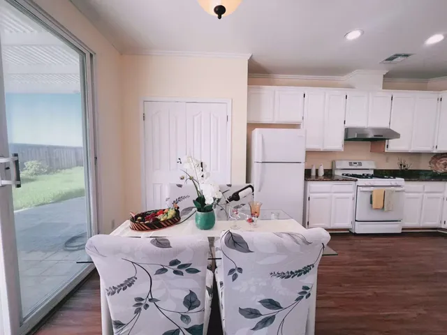 a kitchen with stainless steel appliances granite countertop a stove a refrigerator a sink a dining table and chairs