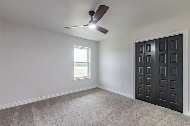 an empty room with a ceiling fan and a window