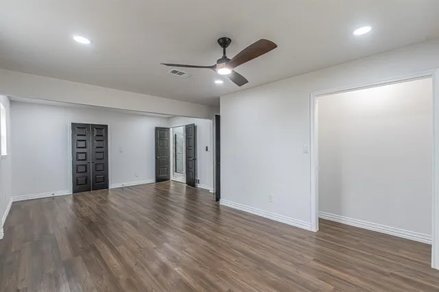 a view of an empty room with a window and wooden floor