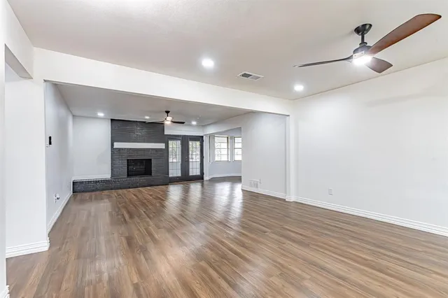an empty room with wooden floor fireplace and windows