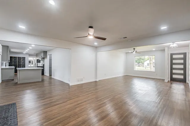 an empty room with wooden floor chandelier and windows