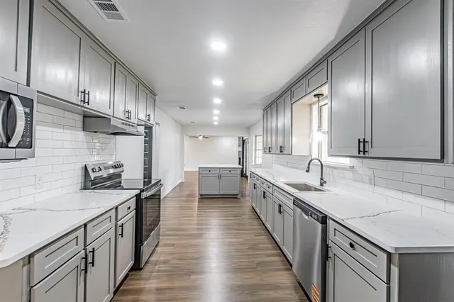 a kitchen with stainless steel appliances granite countertop a sink a stove and a wooden floors