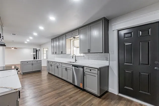 a large kitchen with a large counter top space a sink and cabinets