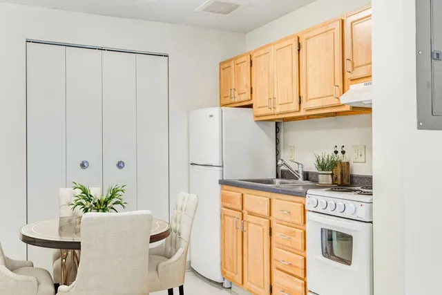 a kitchen with stainless steel appliances granite countertop a white cabinets and a wooden floor