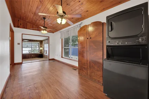 a view of an empty room with wooden floor and a kitchen