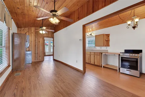 a view of a kitchen with a stove a ceiling fan and wooden floor