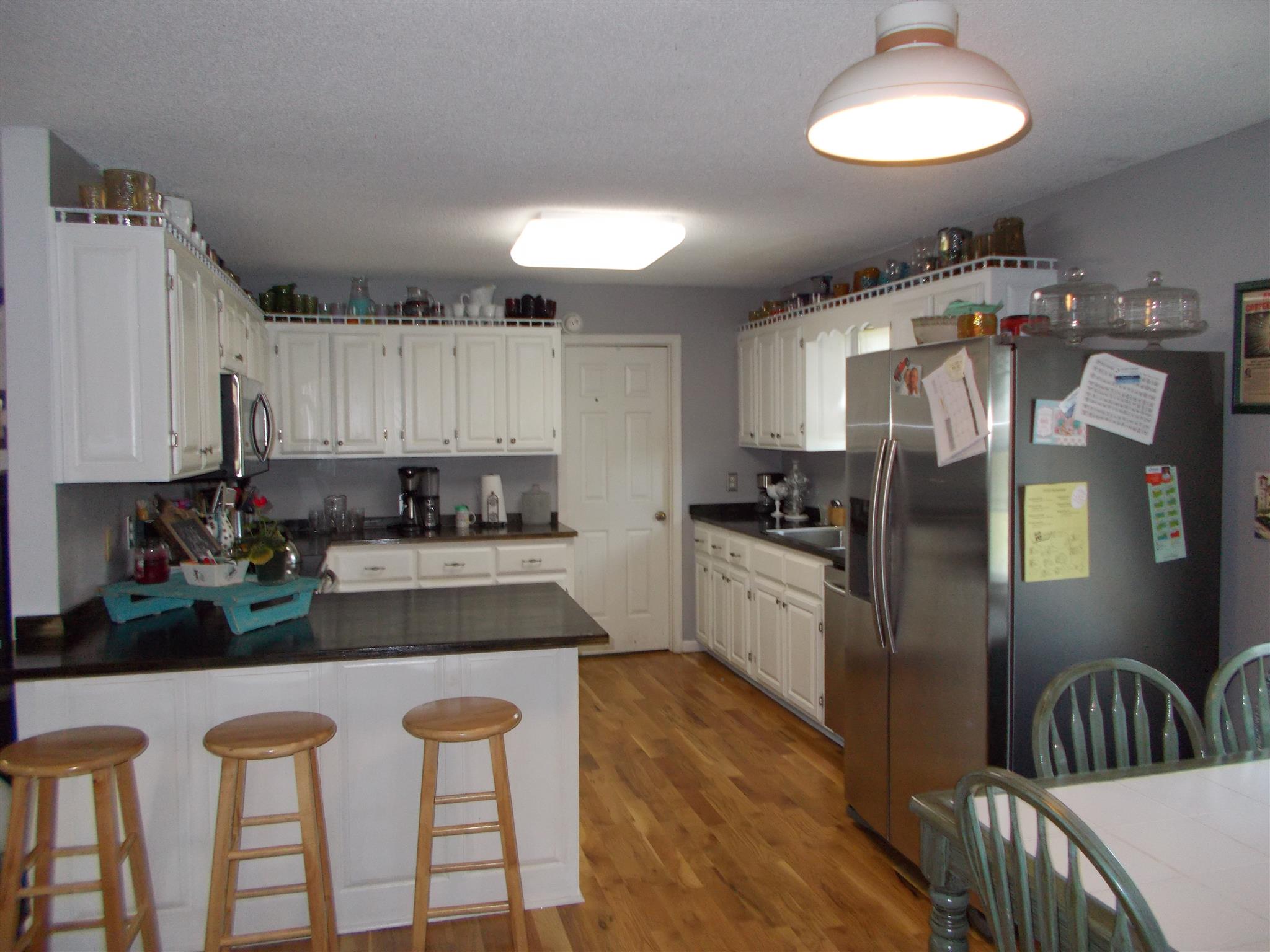 136 Westside Road Lawrenceburg, TN 38464 - Photo 2 of 30 a kitchen with granite countertop a refrigerator a stove a sink and white cabinets with wooden floor
