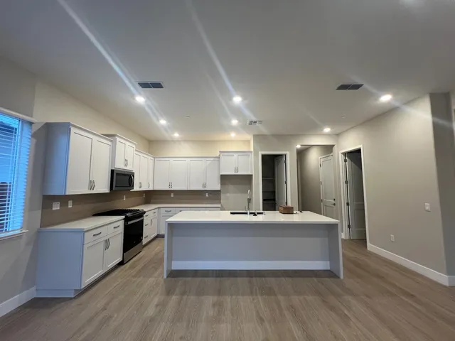 a large kitchen with kitchen island a sink a stove a refrigerator and a stove with wooden floor