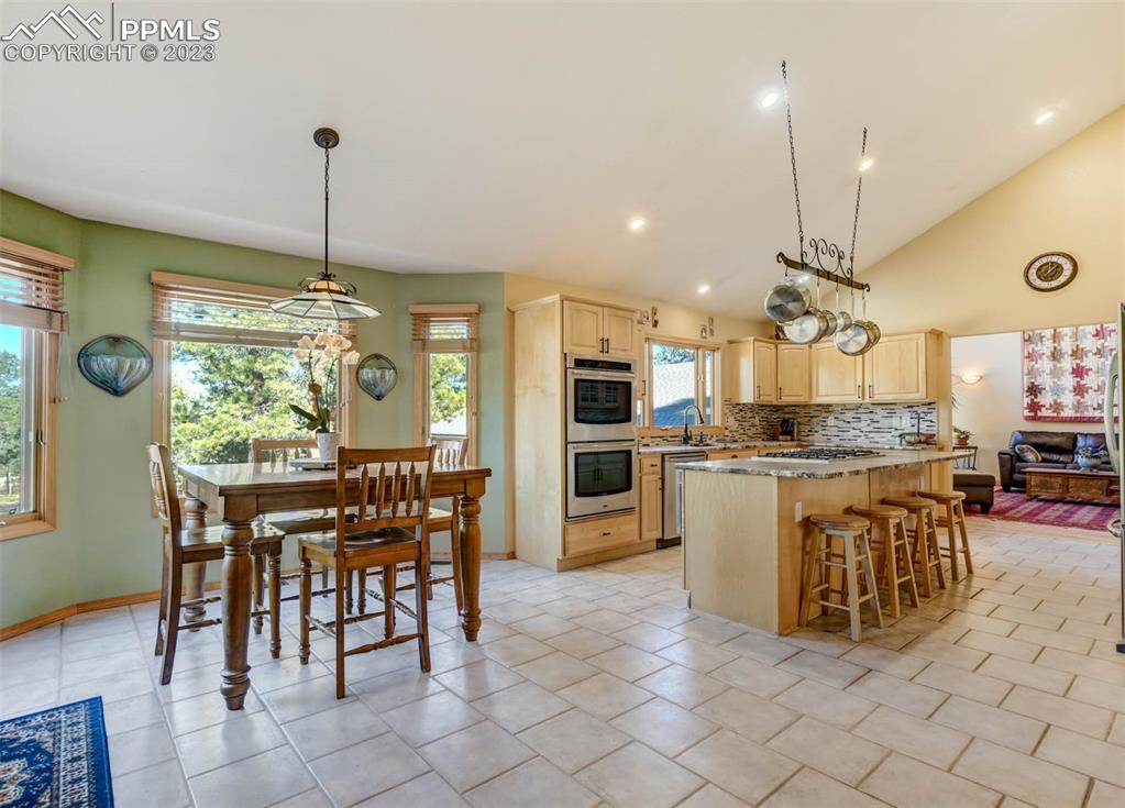 17305 Goshawk Road Colorado Springs, CO 80908 - Photo 20 of 50 a kitchen with kitchen island granite countertop a table chairs sink and cabinets