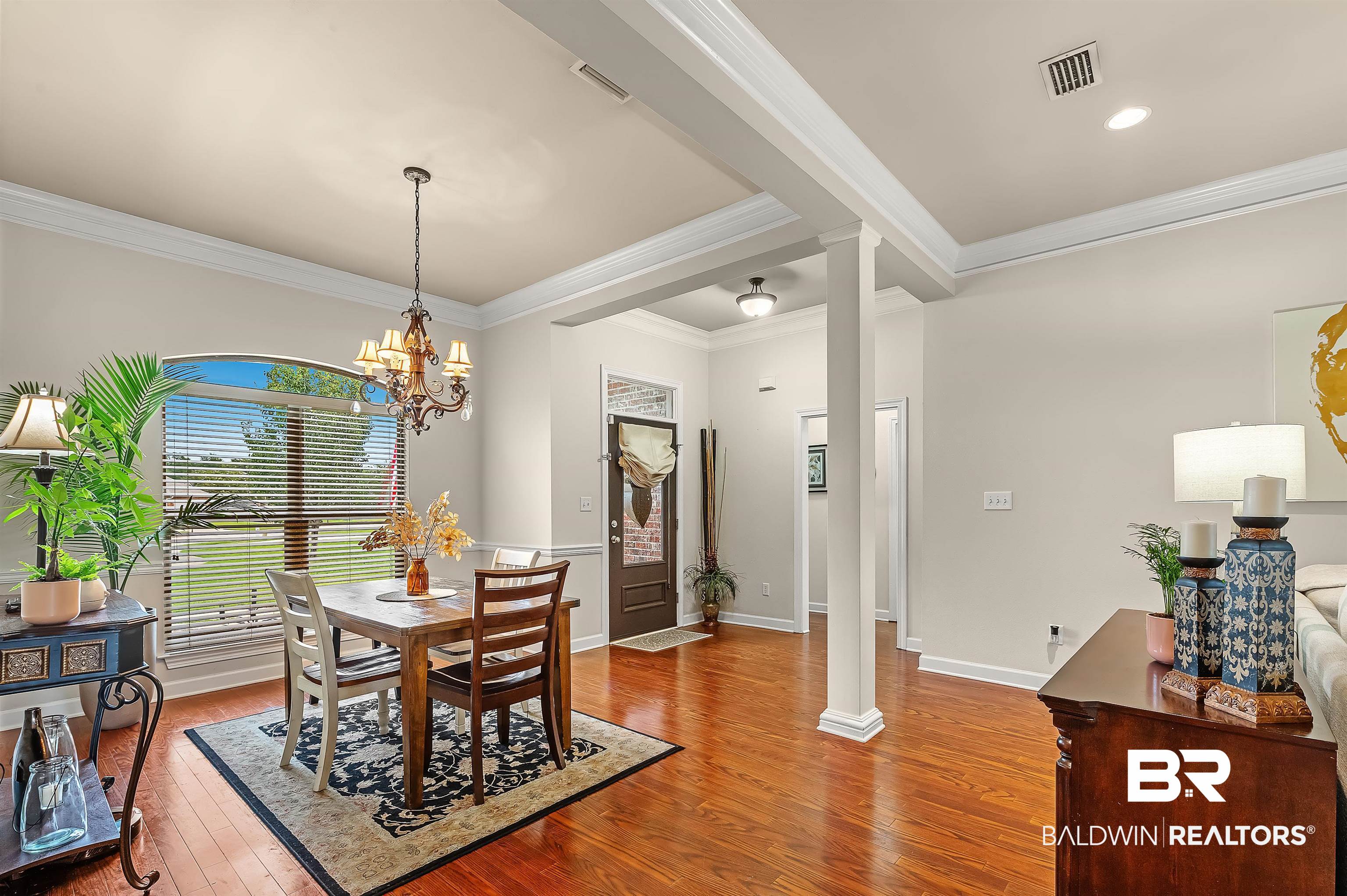 9376 Sable Court Daphne, AL 36526 - Photo 6 of 46 Dining area with crown molding, a chandelier, hardwood / wood-style floors, and decorative columns