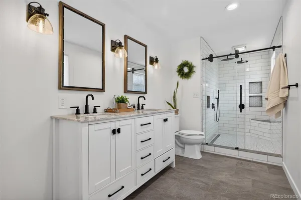 a bathroom with a double vanity sink toilet and shower