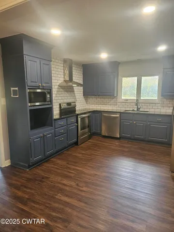 a large kitchen with granite countertop a large counter top stainless steel appliances and cabinets